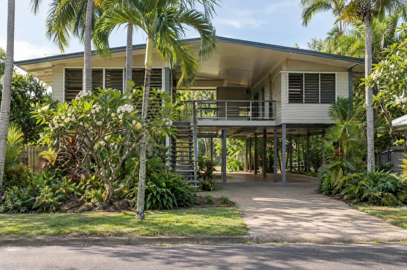 An elevated tropical house with louvres and palms in Darwin